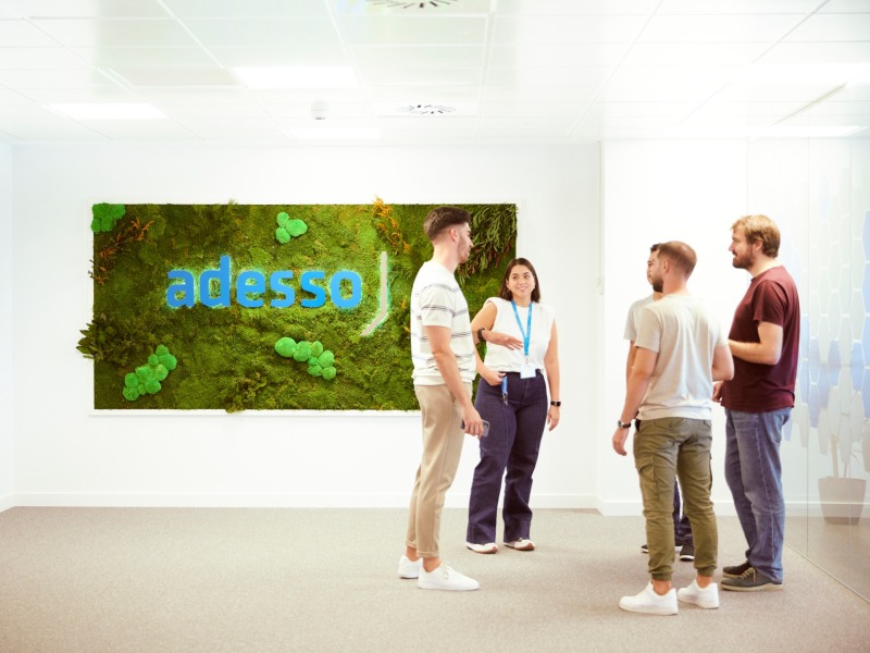 Employees stand in a meeting room and talk to each other